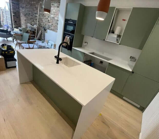Quartz worktops on green kitchen units